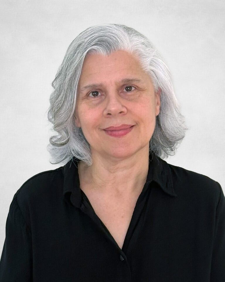 Beverly Wasmund is a middled-aged woman with shoulder-length grey hair. She is wearing a black button-up shirt.