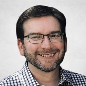 Brent Fawdry is a man with short brown hair, glasses, and a beard. He is wearing a black and white chequered shirt.