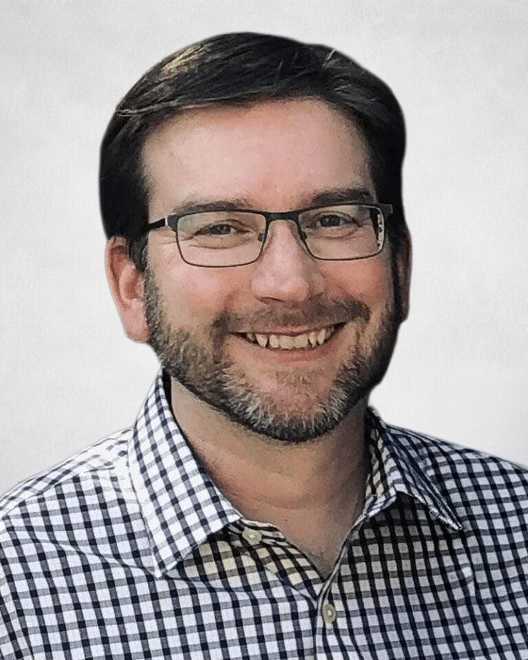 Brent Fawdry is a man with short brown hair, glasses, and a beard. He is wearing a black and white chequered shirt.