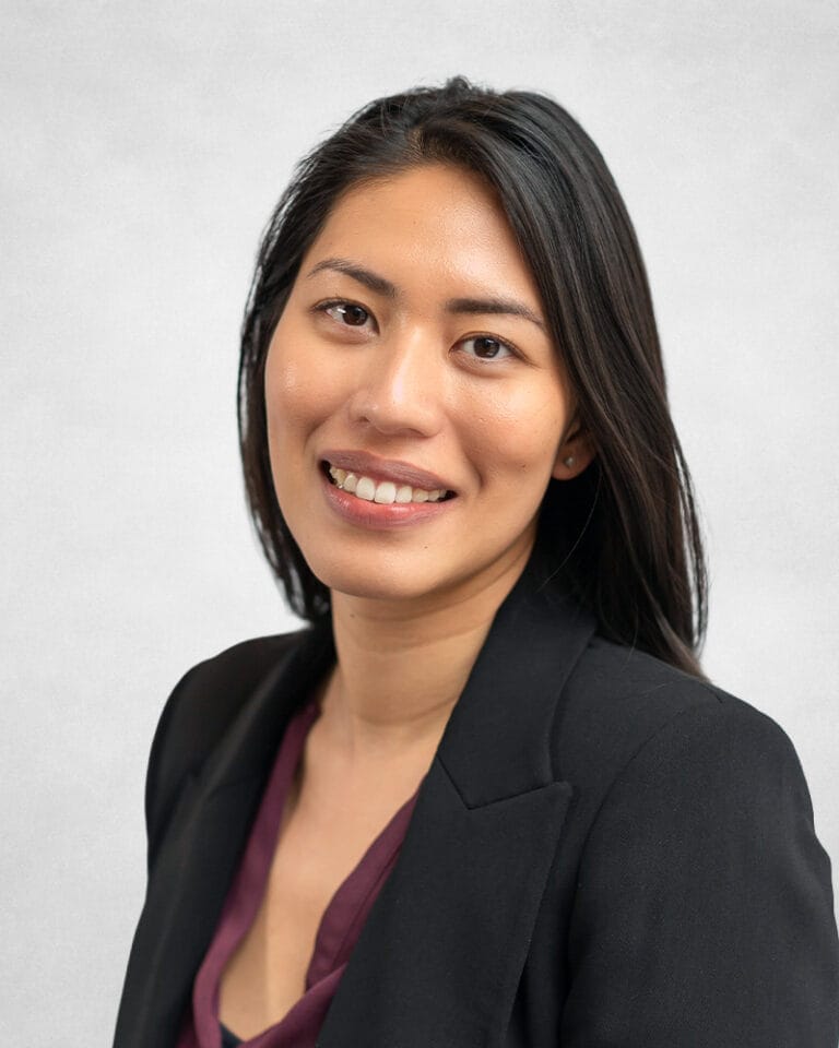 Jessica Lee is a woman with long black hair. She is wearing a black blazer and burgundy top.