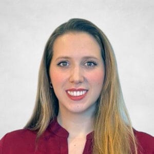 Julianna De Souza is a woman with long, straight blonde hair wearing a burgundy blouse.