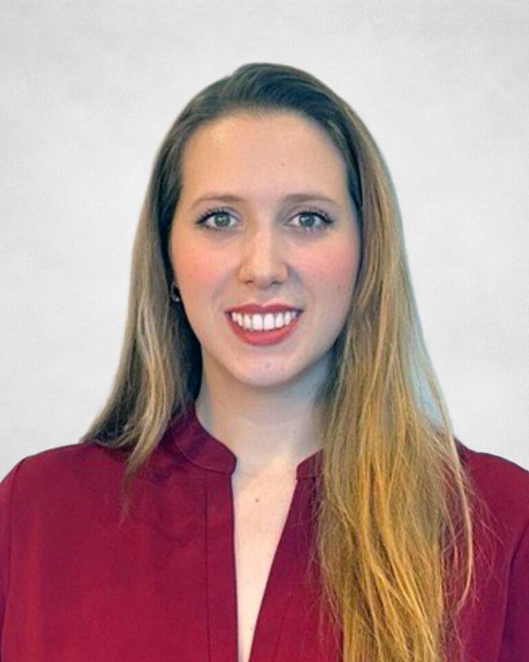 Julianna De Souza is a woman with long, straight blonde hair wearing a burgundy blouse.