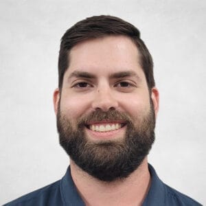 Mike Askew is a man with short dark hair and a full beard. He is wearing a dark blue collared shirt.