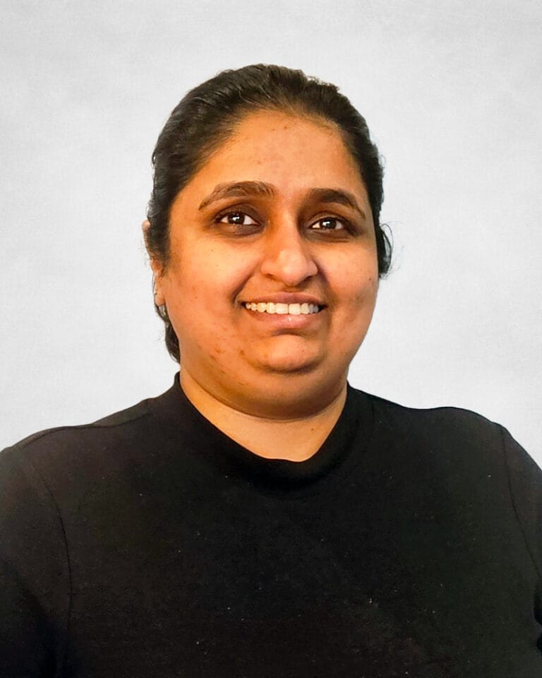 Samantha Singh is a woman with dark hair pulled back. She is wearing a black T-Shirt.