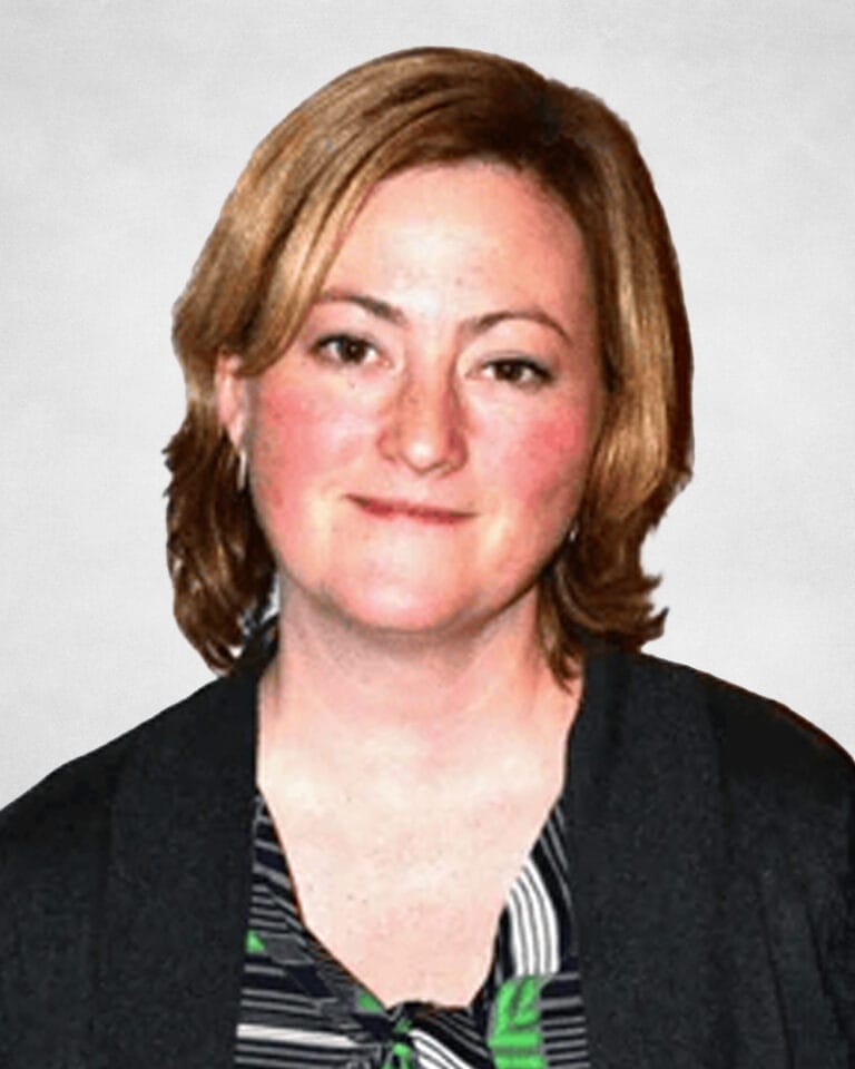 Susan Andrews is a woman with fair skin and short, light brown hair. She is wearing a dark top over a patterned blouse.