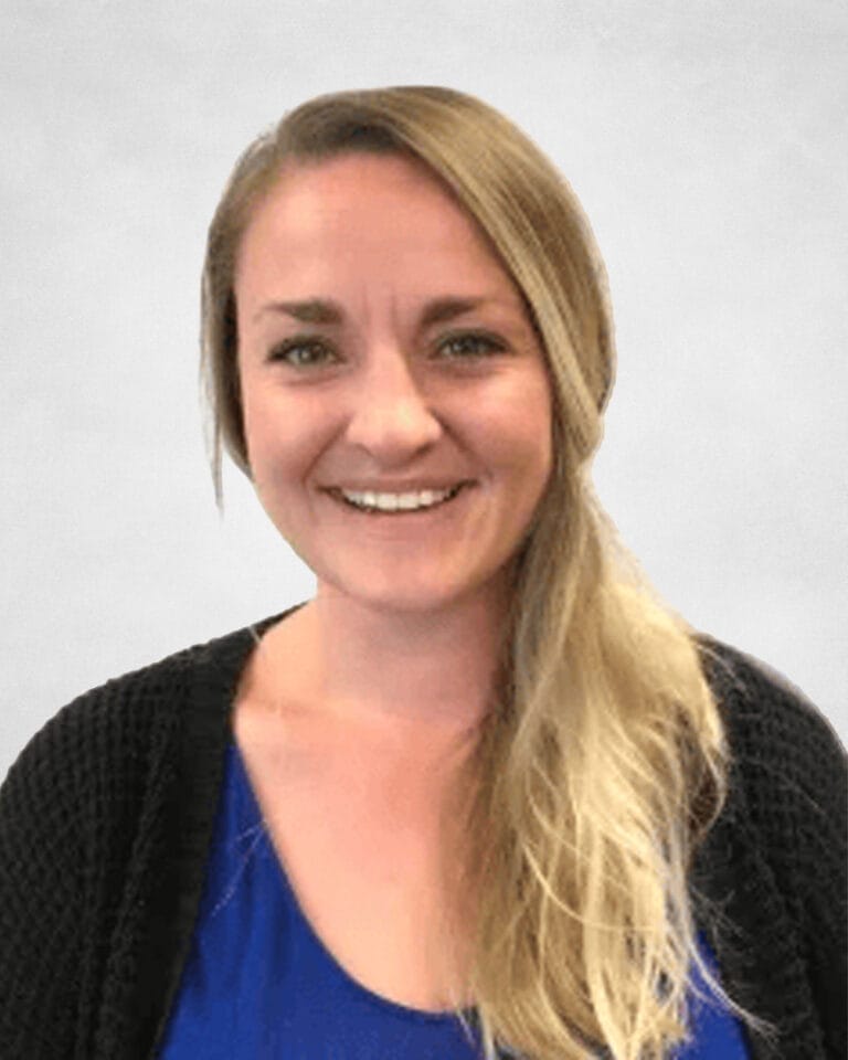 Taylor Schmidt is a woman with long blonde hair. She is wearing a blue top and a black cardigan.
