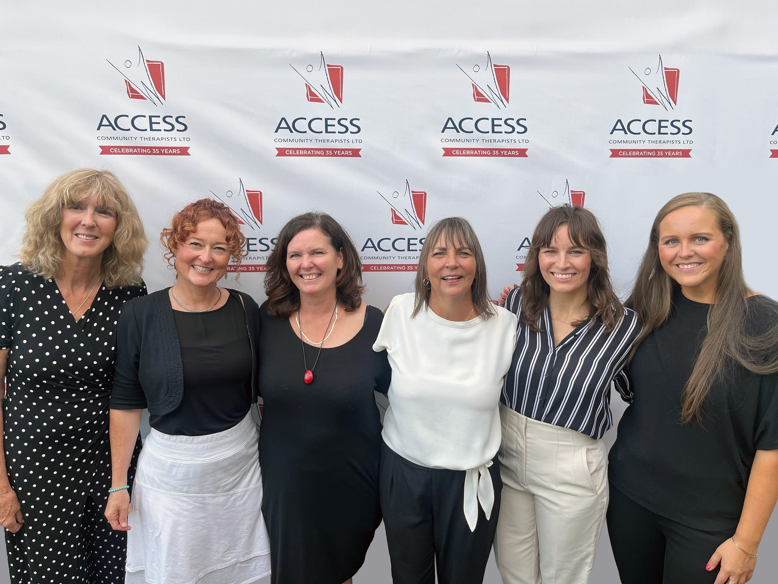 The Access Community Therapists Team of Directors is pictured. Behind them is the Access Community Therapists logo.